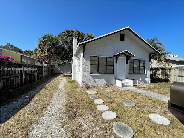 exterior space featuring a chimney, fence, and stucco siding