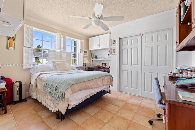 bedroom featuring a closet, ornamental molding, a ceiling fan, a textured ceiling, and light tile patterned flooring