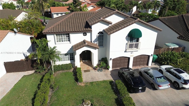 view of front of house with a garage, fence, decorative driveway, and a tile roof