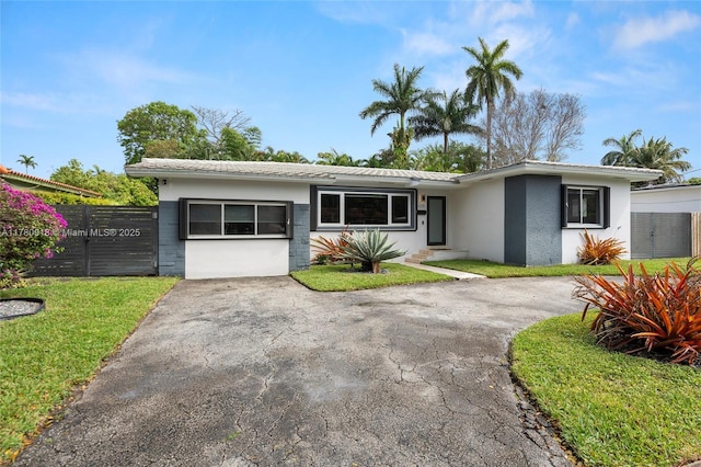 ranch-style house with fence, a front yard, and concrete block siding
