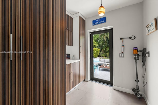 doorway to outside featuring baseboards and light tile patterned floors
