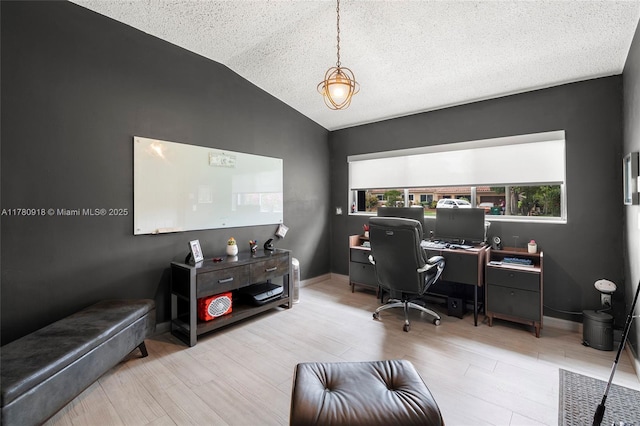 home office featuring vaulted ceiling, wood finished floors, a textured ceiling, and baseboards