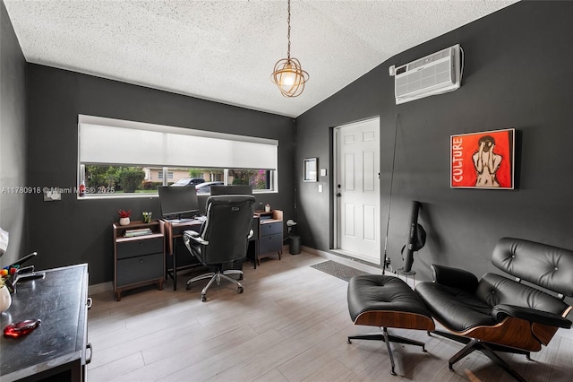 office area with a textured ceiling, light wood-type flooring, baseboards, lofted ceiling, and a wall unit AC