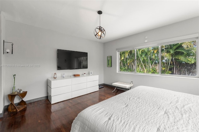 bedroom with baseboards, wood finished floors, and multiple windows