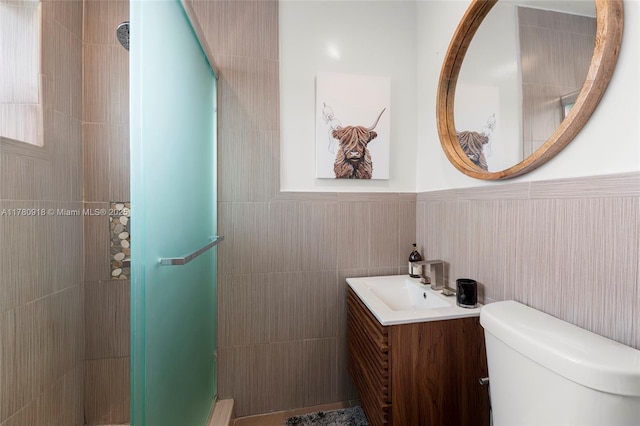 bathroom featuring a shower stall, toilet, vanity, and tile walls