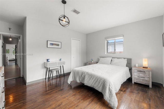 bedroom featuring visible vents, baseboards, wood finished floors, and a closet