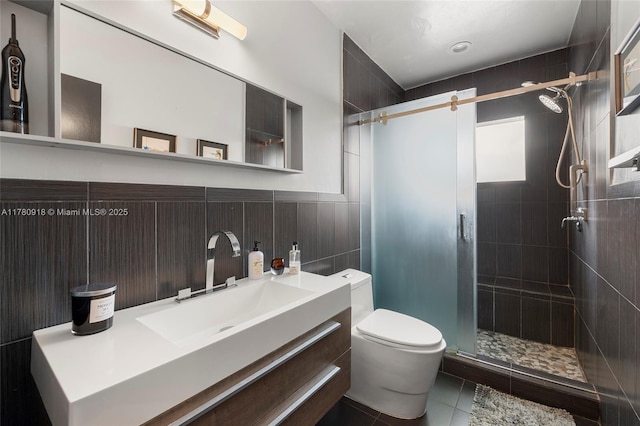 bathroom with a shower stall, vanity, tile walls, toilet, and tile patterned flooring