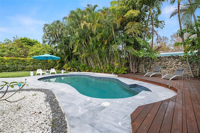 outdoor pool with a wooden deck and a patio area