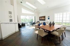 dining room with high vaulted ceiling, plenty of natural light, baseboards, and a skylight