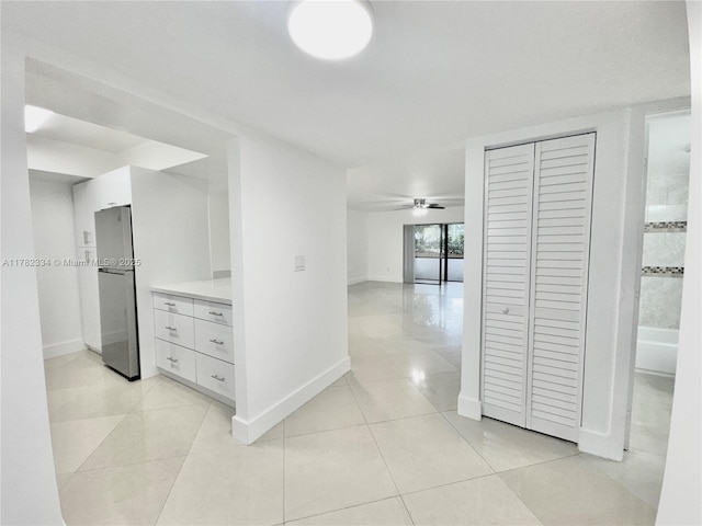 hall featuring baseboards and light tile patterned floors