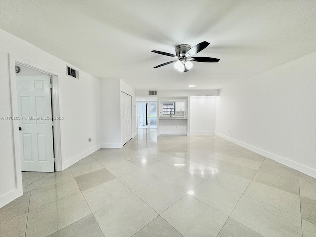 empty room with ceiling fan, baseboards, light tile patterned flooring, and visible vents