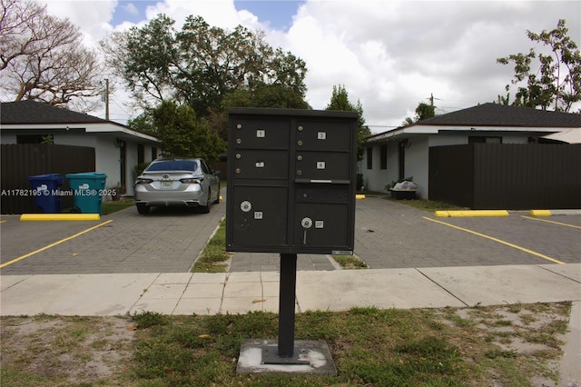 exterior space featuring mail area, fence, and a parking lot