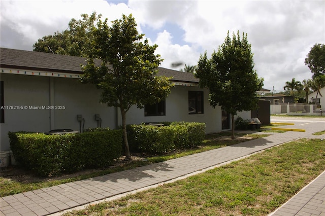 view of side of home with roof with shingles and stucco siding