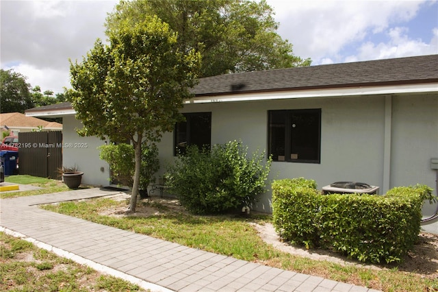 ranch-style home with a shingled roof and central air condition unit