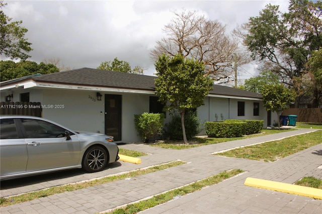 ranch-style home with roof with shingles and stucco siding