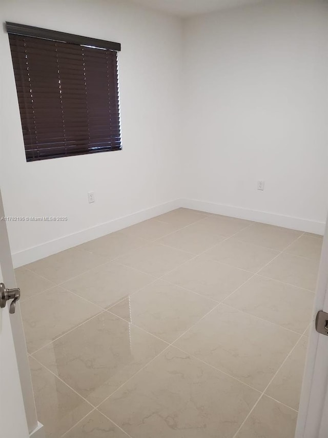 spare room with light tile patterned floors and baseboards