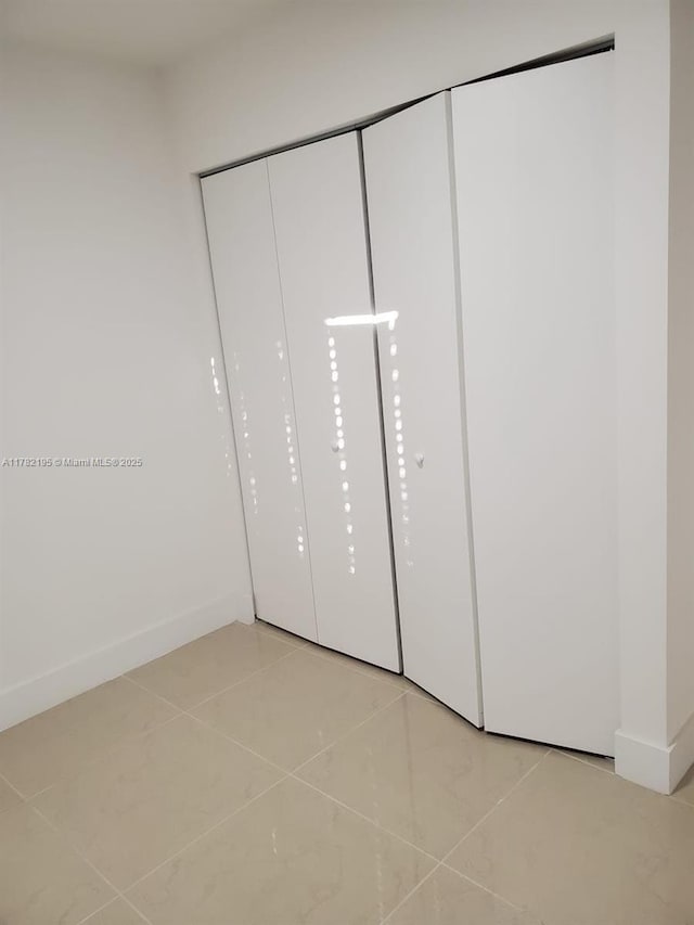 unfurnished bedroom featuring light tile patterned floors and baseboards