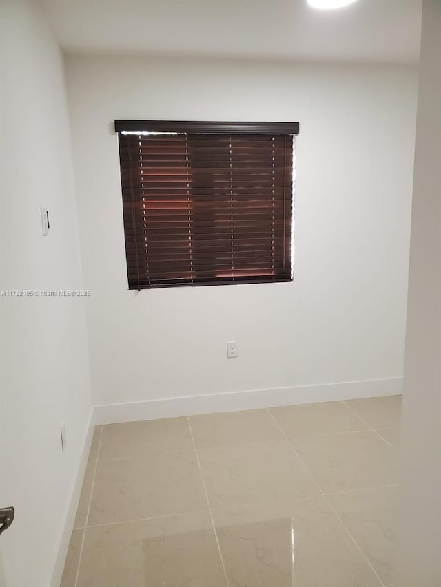 spare room with baseboards and light tile patterned flooring