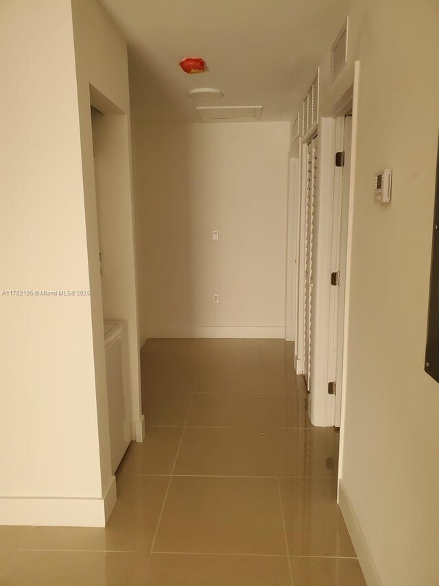corridor featuring tile patterned flooring, visible vents, and baseboards