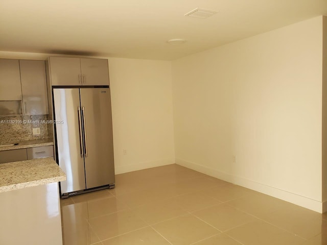 empty room featuring light tile patterned floors, baseboards, and visible vents