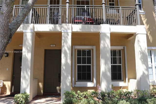 entrance to property featuring a balcony and stucco siding