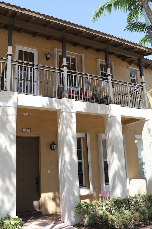 property entrance with stucco siding and a balcony
