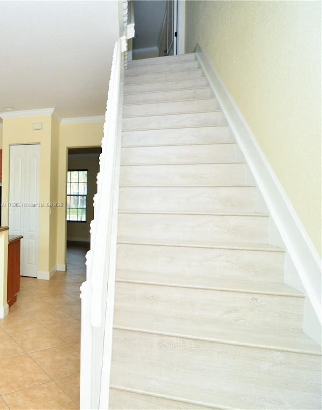 staircase featuring ornamental molding, baseboards, and tile patterned flooring