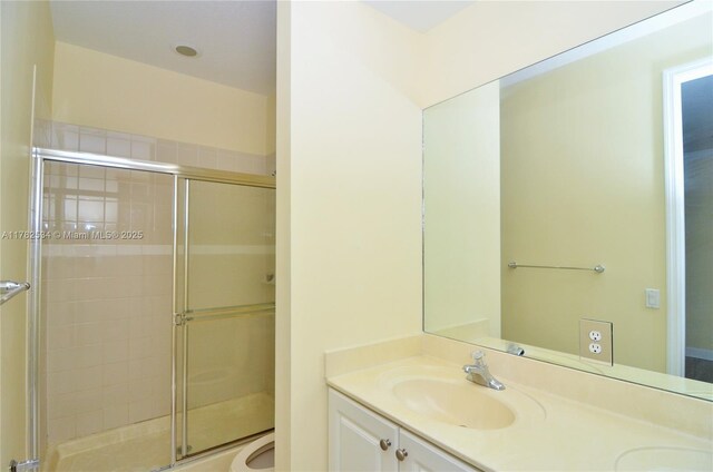 bathroom with a shower stall, double vanity, a sink, and toilet