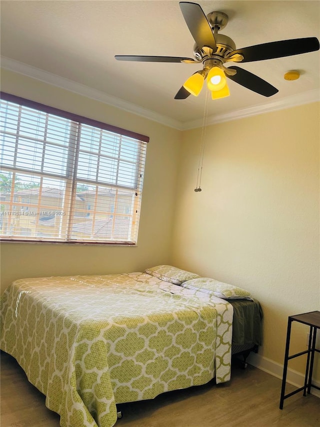 bedroom with a ceiling fan, wood finished floors, baseboards, and ornamental molding