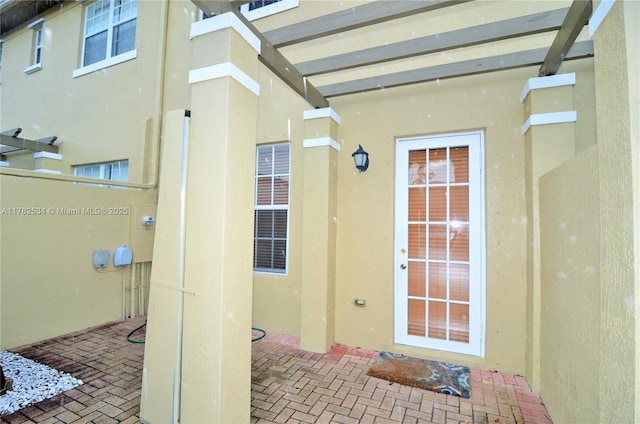 view of exterior entry featuring a patio and stucco siding