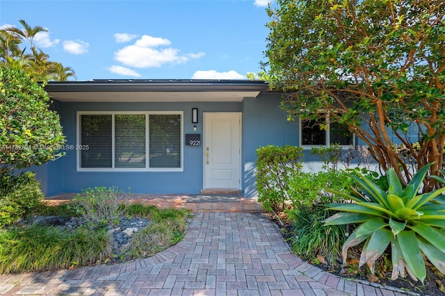 entrance to property with a porch and stucco siding