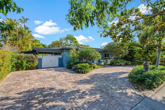 ranch-style house with a gate, fence, and stucco siding