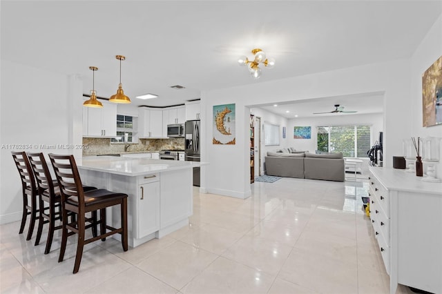 kitchen featuring white cabinets, light countertops, stainless steel appliances, open floor plan, and backsplash