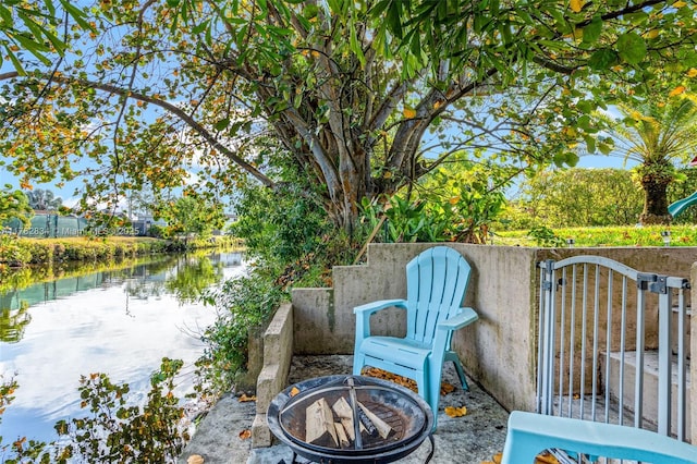 view of patio with a water view, fence, a gate, and an outdoor fire pit