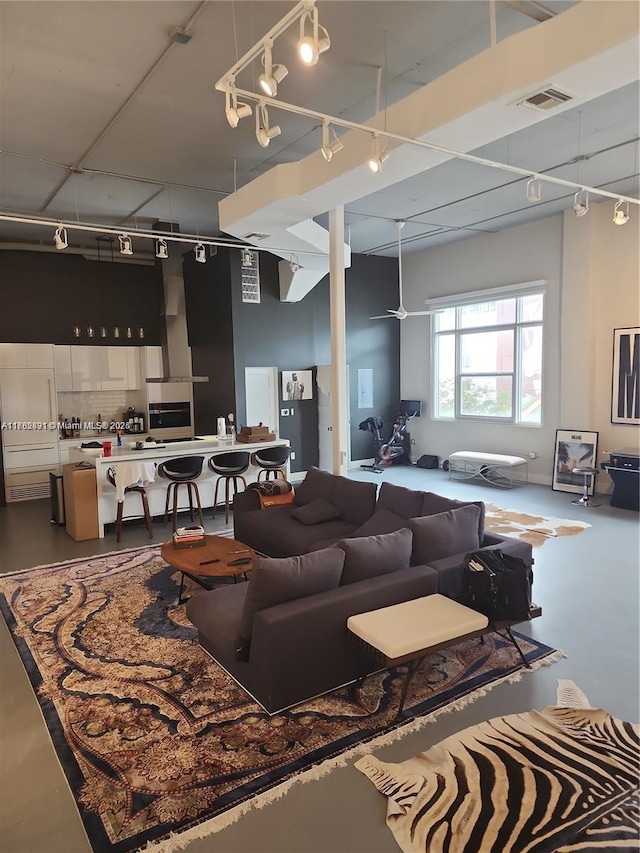 living area with concrete floors, visible vents, ceiling fan, and track lighting