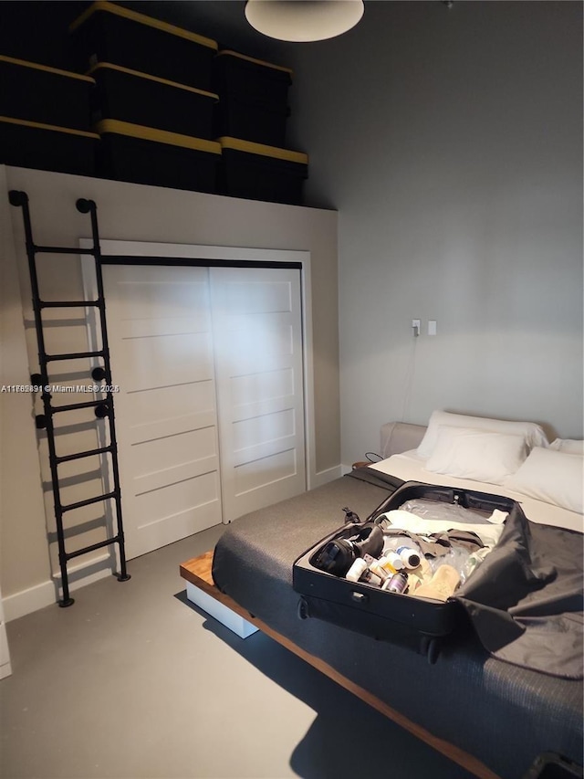 bedroom featuring finished concrete floors and baseboards