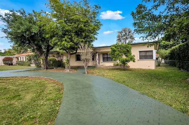 single story home with stucco siding, fence, a front lawn, and curved driveway