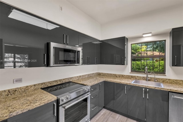 kitchen featuring dark cabinets, light wood-style flooring, visible vents, a sink, and stainless steel appliances
