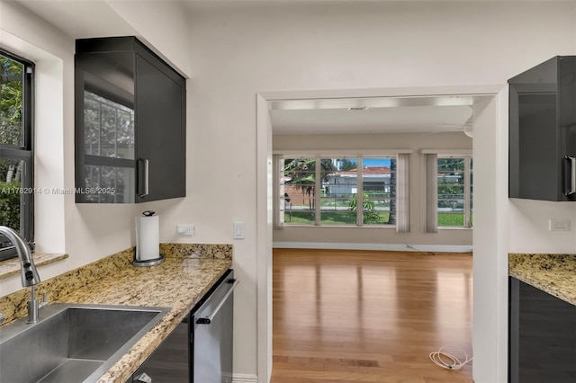 bar with a sink, stainless steel dishwasher, wood finished floors, and a healthy amount of sunlight