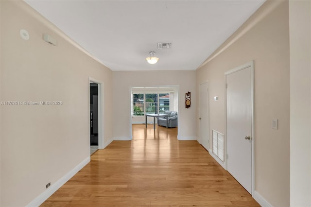 corridor featuring visible vents, baseboards, and light wood-style floors