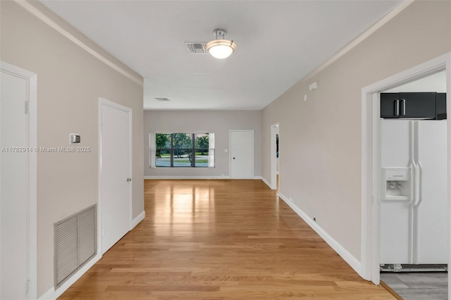 hall featuring visible vents, baseboards, and light wood-type flooring