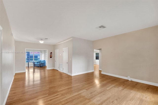 empty room with light wood-type flooring, baseboards, and visible vents