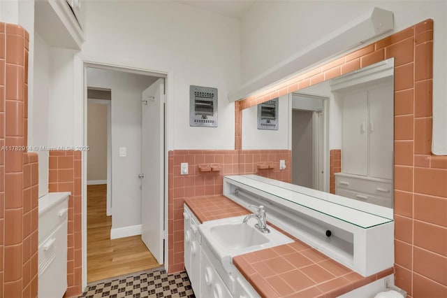 bathroom featuring tile patterned floors, tile walls, vanity, and wainscoting