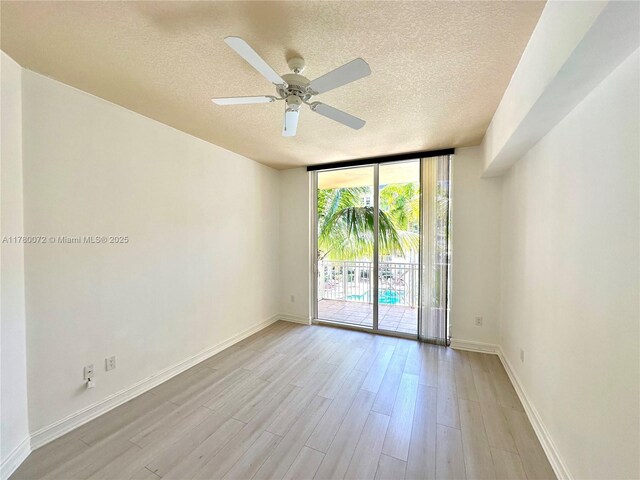 3001 NE 185th St Unit 336, Aventura, FL 33180 - spare room featuring baseboards, a textured ceiling, a ceiling fan, floor to ceiling windows, and light wood-style floors