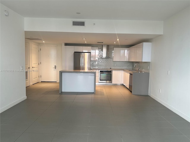 kitchen featuring wall chimney range hood, visible vents, appliances with stainless steel finishes, tile patterned floors, and decorative backsplash