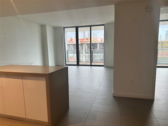 spare room featuring a healthy amount of sunlight, light tile patterned floors, and baseboards