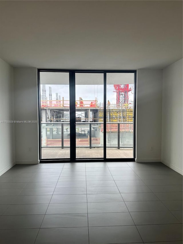 unfurnished room featuring tile patterned floors, baseboards, and expansive windows
