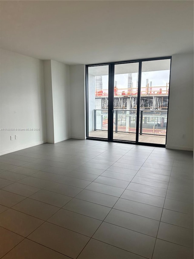 spare room with a city view, tile patterned floors, baseboards, and expansive windows