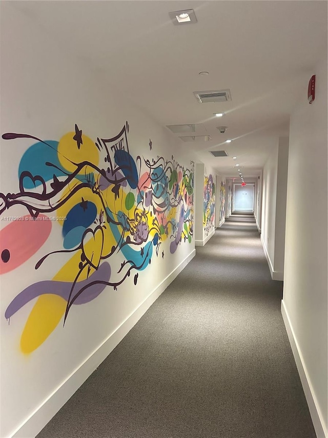 hallway with carpet flooring, visible vents, and baseboards