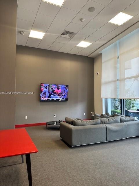 living area with visible vents and carpet